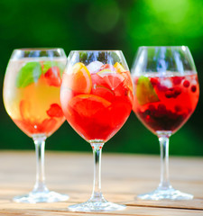 Summer cocktail. Fruit cocktail on green background. Citrus fruits, berries, strawberries, blueberries, mint, ice.