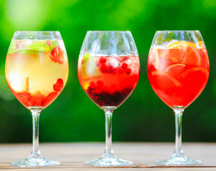 Summer cocktail. Fruit cocktail on green background. Citrus fruits, berries, strawberries, blueberries, mint, ice.