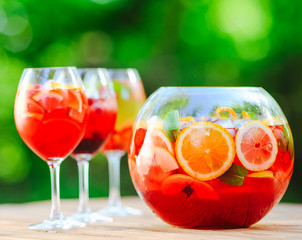 Summer cocktail. Fruit cocktail on green background. Citrus fruits, berries, strawberries, blueberries, mint, ice.