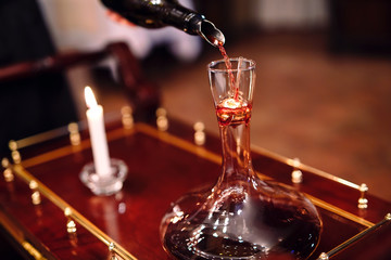 A sommelier pouring red wine into decanter