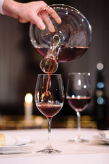 A sommelier pouring red wine into decanter