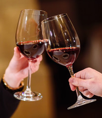 Man and woman drinking red wine. In the picture, close-up hands with glasses.