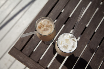 ice cappuchino and latte coffee with cocktail tube on a light and dark wooden table in the layout