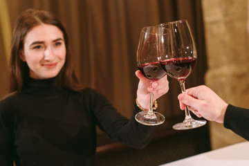 Beautiful young couple with glasses of red wine in luxury restaurant