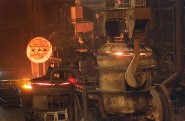 Melting of metal in a steel plant. High temperature in the melting furnace. Metallurgical industry. Factory for the manufacture of metal pipes. Bucket for feeding metal into molds.
