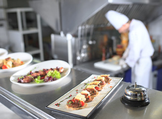 the distribution table in the kitchen of the restaurant. the chef prepares a meal on the background of the finished dishes.