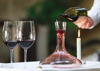 A sommelier pouring red wine into decanter