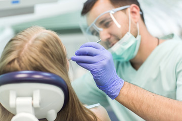 Close-up picture of young woman sitting in the dentist's chair with opened mouth at dentist's office while having examination.