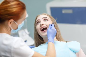 female dentist checking patient girl teeth