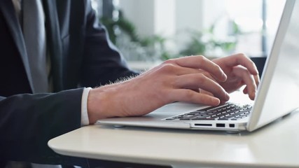Pan closeup shot of hands of unrecognizable businessman typing on laptop while working in the office - Powered by Adobe