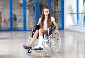 A young girl in a wheelchair is standing in the corridor of the hospital.