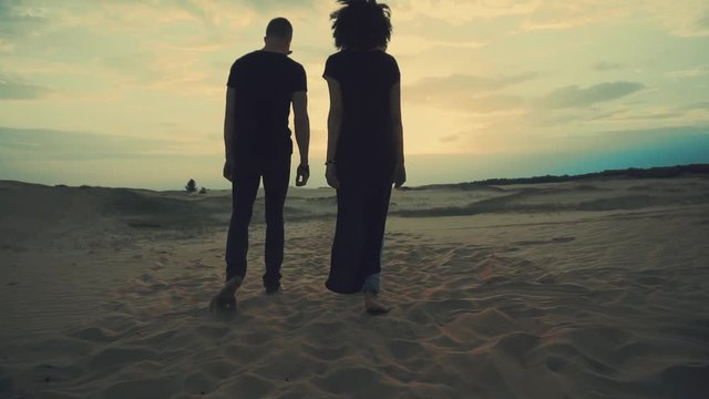 Couple walking in desert at sunset