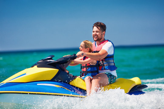 happy, excited family, father and son having fun on jet ski at summer vacation