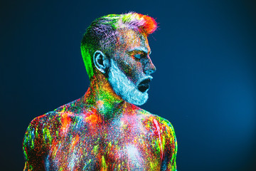 Concept. Portrait of a bearded man. The man is painted in ultraviolet powder.