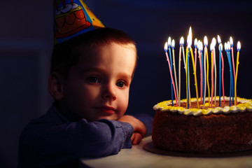 Birthday. A little boy blows out candles on the stoke.