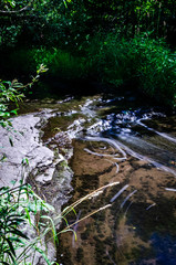 Vertical long exposure close-up of a shallow stream flowing over rocks
