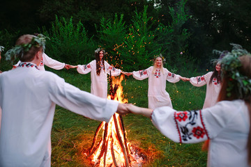 Midsummer. Young people in Slavic clothes circle dance around a bonfire in the forest.