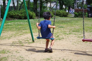 公園のブランコで遊ぶ男の子