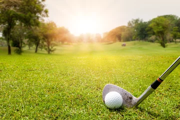 Rolgordijnen Golf club and golf ball in grass in sunrise. © Nischaporn