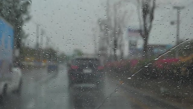 slow motion, car driving in rainy day, wiper cleaning water on windshield