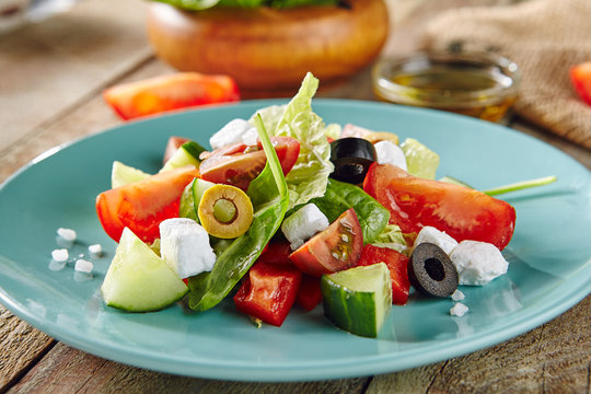 Greek Salad in Blue Plate on Wooden Rustic Background
