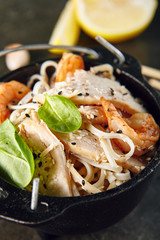 Noodles with Shrimps, Chicken, in Metal Bowler with Sesame Seeds on Natural Dark Stone Background
