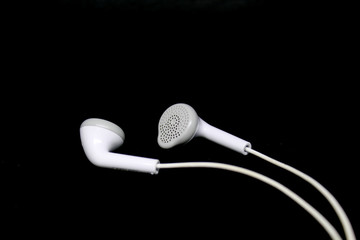 White wired earphones on black background.