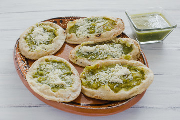 Mexican sopes with grated cheese and green salsa, mexican food spicy in mexico