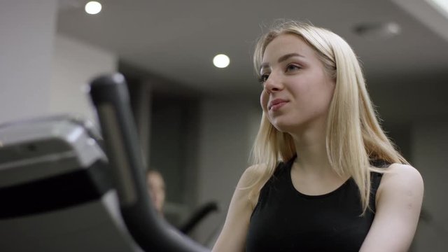 lovely girl in black sport wear hardly work on exercise bike with focus on hands in the new gym