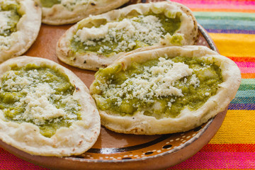 Mexican sopes with grated cheese and green salsa, mexican food spicy in mexico
