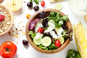 Close up of mixed vegetables salad, muesli and fresh fruits on white background.