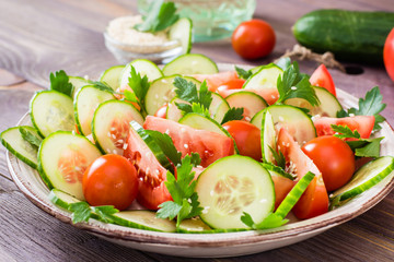 Vegetable salad of fresh cucumbers, tomatoes, parsley and sesame seeds on a plate