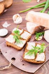 Sandwiches from rye bread, salted bacon and dill on a cutting board on a wooden table