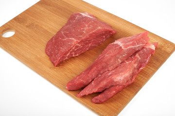 Raw beef piece and slices on wooden cutting board isolated on white background