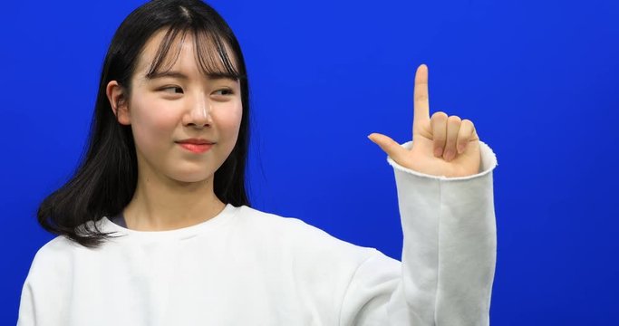 Asian beautiful girl making sign language "i love you" with fingers on blue screen