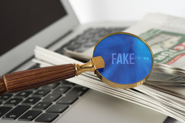Ein Computer, eine Zeitung und eine Lupe mit dem Wort Fake News
