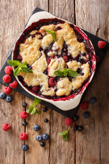 Summer berry cake with raspberry berries, currants and blueberries close-up in a baking dish. vertical top view
