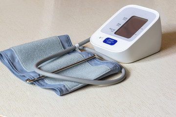White electronic tonometer close-up on a wooden table. Measurement of blood pressure. Healthy...