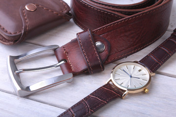 Men's accessories for business and rekreation. Leather belt, wallet, watch and smoking pipe on wood background.. Top view composition.