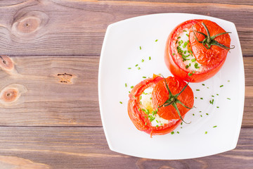 Fresh tomatoes baked with cheese and chicken egg on a plate on a wooden table. Top view. Copy space