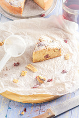 A piece of banana cake with nuts, sesame and cranberry on a wooden table