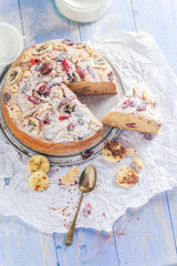 A sliced banana cake with nuts, sesame and cranberry on a wooden table