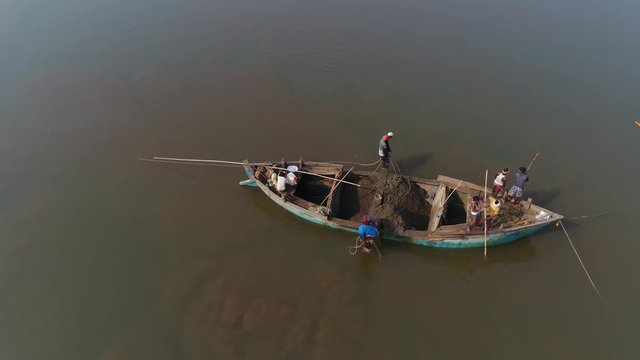 Indians on the boat mined clay from the bottom of the river by hand, using the sticks of buckets and ropes. Shooting with a drone.