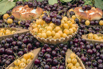 Colorful cherries decorated with Bulgarian folk wooden bowls and home-made bread with cheese. Kyustendil, Bulgaria.