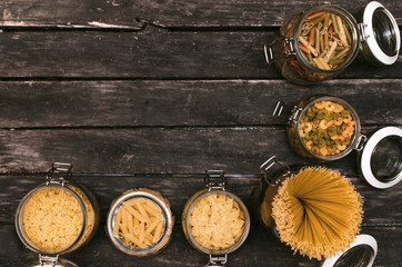 Pasta collection in a glass jars on the kitchen table. Top view.