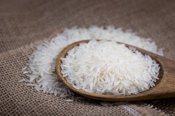 rice whole grains with wooden spoon on sack background
