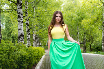 Beautiful young woman near green trees in the park