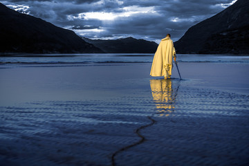 Portrait of assassin in white costume with the sword at the sea. He is posing near water with...