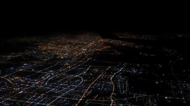 4K Aerial view lights of houses and roads of Shanghai city. Top view from airplane window at night. Plane flying above China. Elevated view from aircraft fly at nighttime over illuminated big town-Dan