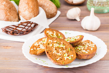 Fresh rye garlic croutons with dill on a plate on a wooden table